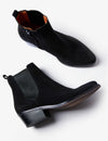 A pair of black suede Chelsea-style ankle boots with elastic side panels and low block heels, shown from side and angled top views on a light gray background.
