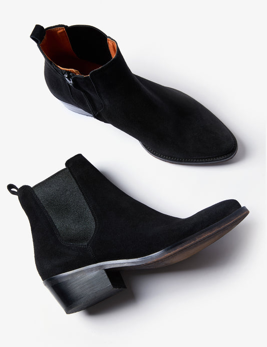 A pair of black suede Chelsea-style ankle boots with elastic side panels and low block heels, shown from side and angled top views on a light gray background.