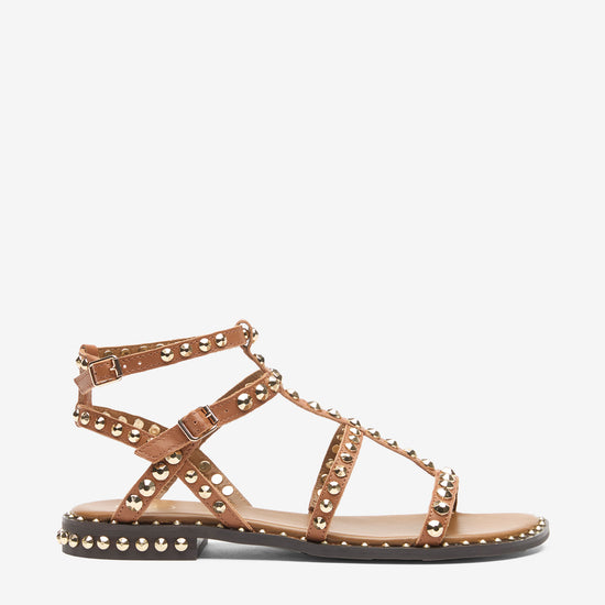 Tan sandal with metal straps and studs on a white background side view