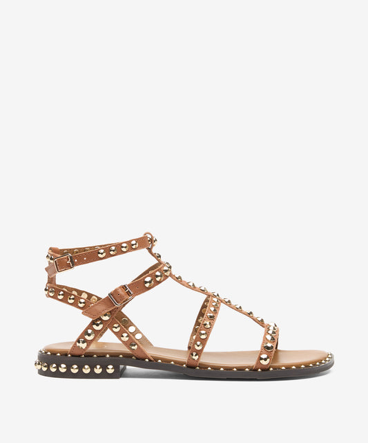 Tan sandal with metal straps and studs on a white background side view