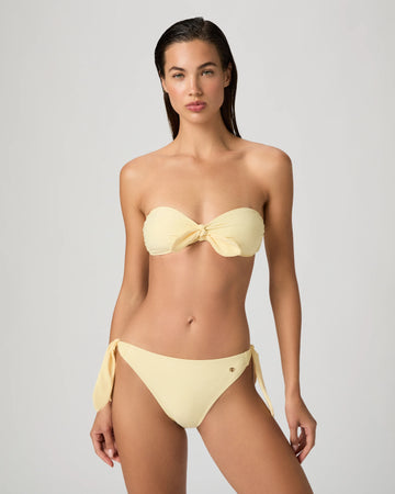 Woman wearing a yellow bikini from Paige against a gray background