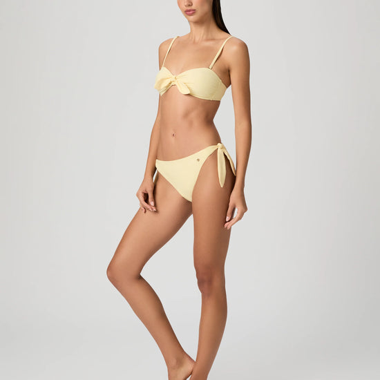 Woman wearing a yellow bikini from Paige against a white background