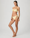 Woman wearing a yellow bikini from Paige against a white background