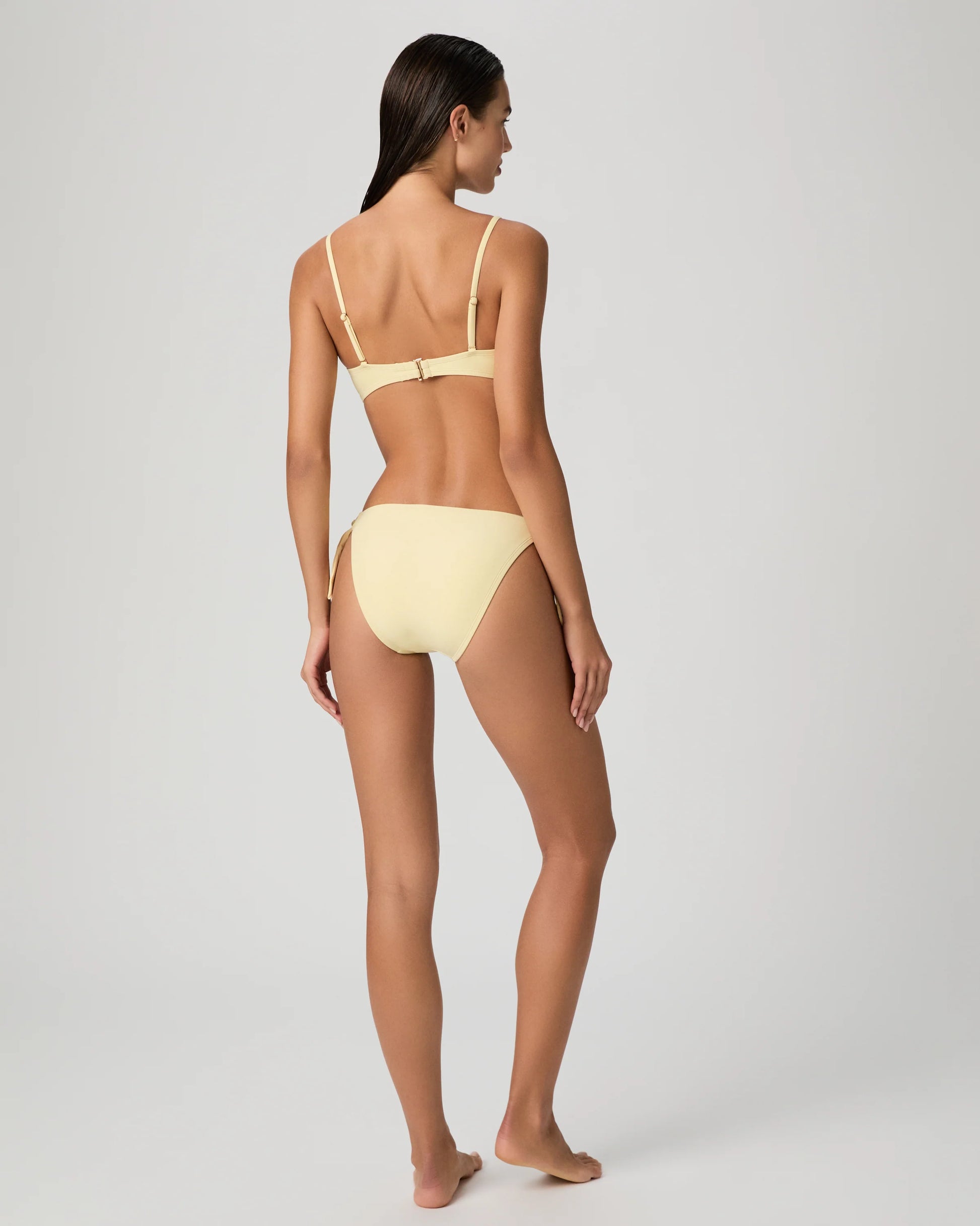 Woman wearing a yellow bikini from Paige on a white background