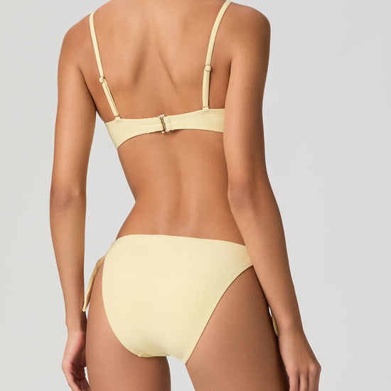 Woman wearing a yellow bikini from Paige against a plain background