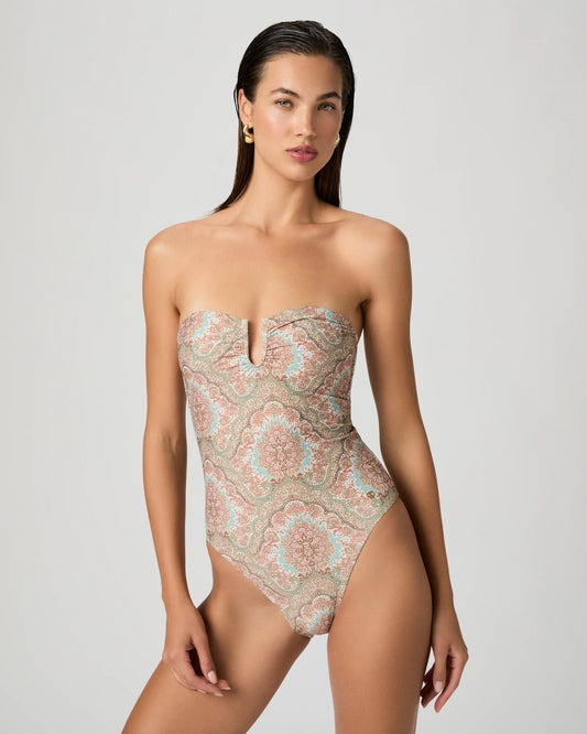 Woman wearing a strapless patterned swimsuit from Paige on a plain background
