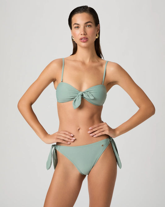 Woman wearing a light green bikini from Paige against a plain background