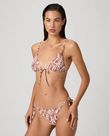 Woman wearing a pink patterned bikini against a white background