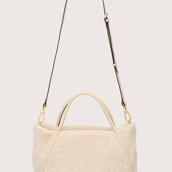 Reverse of cream faux fur bag with cross body strap