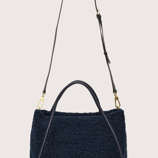 Reverse of navy faux shearling bag with cross body strap