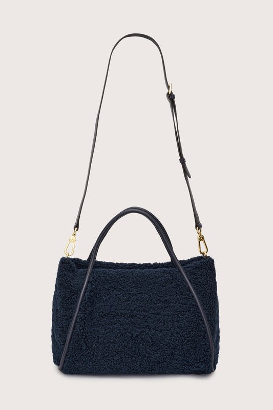 Reverse of navy faux shearling bag with cross body strap