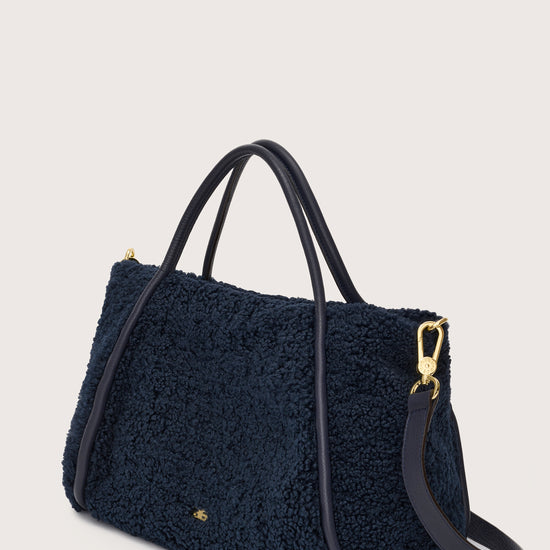 Side view of navy faux shearling bag