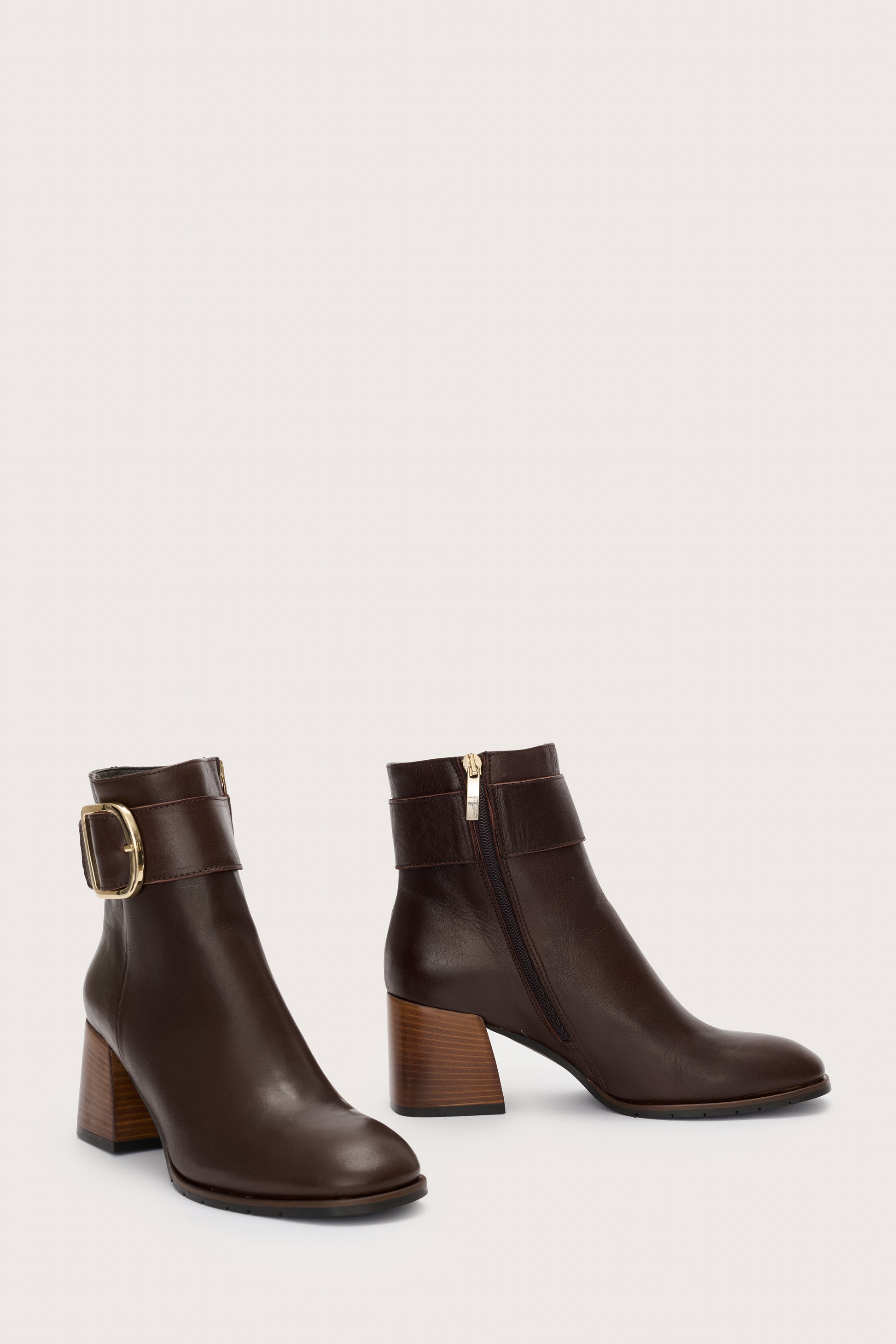 Side view of brown leather boots with gold buckle detail at the ankle