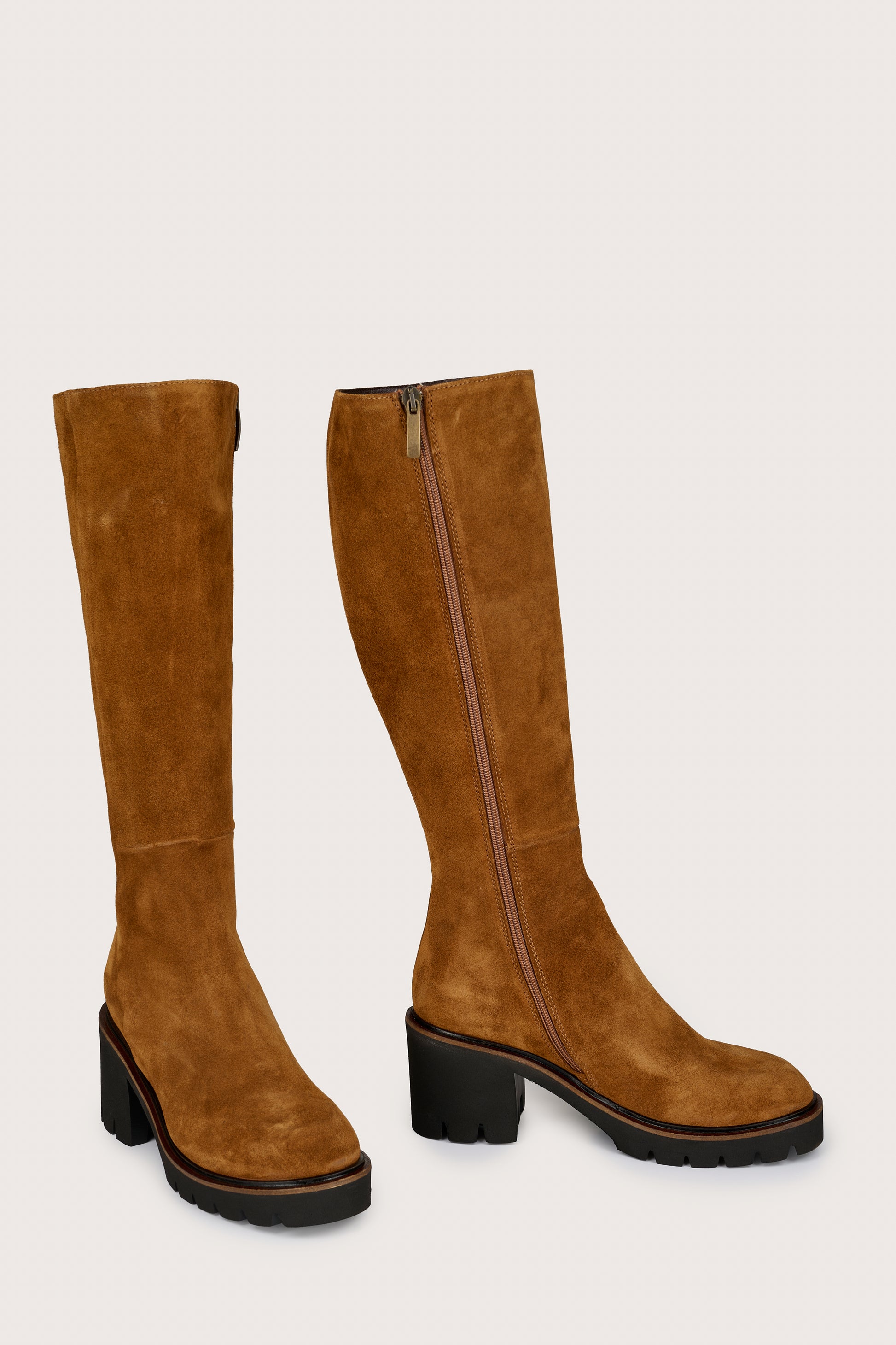 Pair of tan knee-high boots on a light gray background