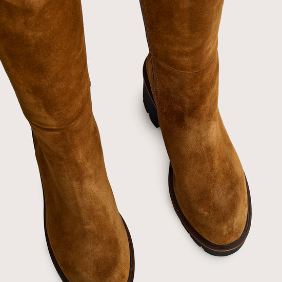 Tan suede knee-high boots on a light gray background