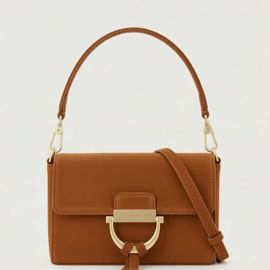 tan suede handbag with gold toned hardwear and a removable cross body strap