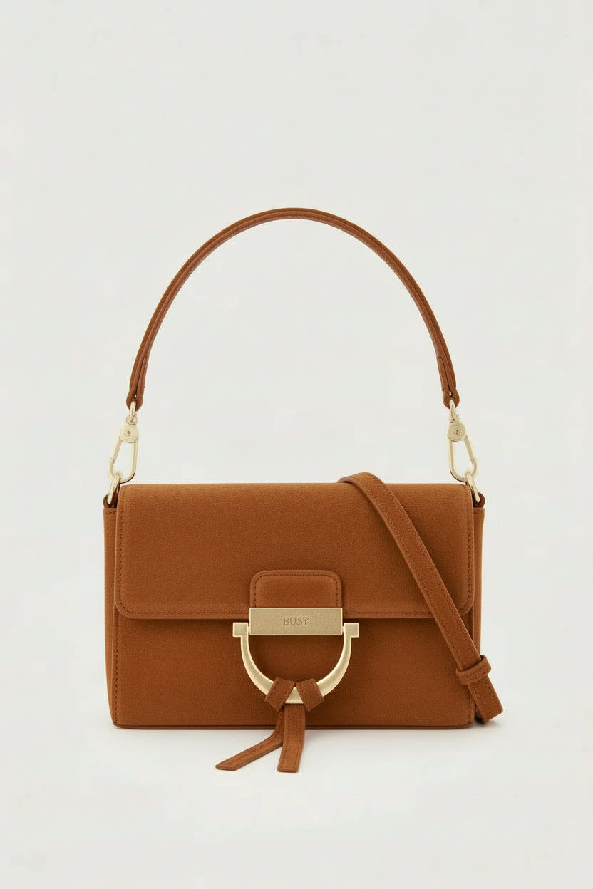 tan suede handbag with gold toned hardwear and a removable cross body strap