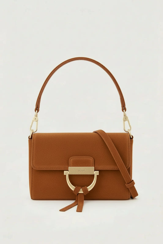 tan suede handbag with gold toned hardwear and a removable cross body strap