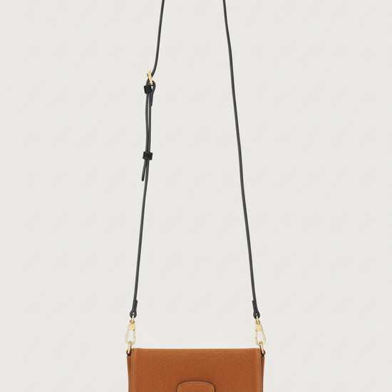 Tan suede handbag with a gold clasp on a light gray background