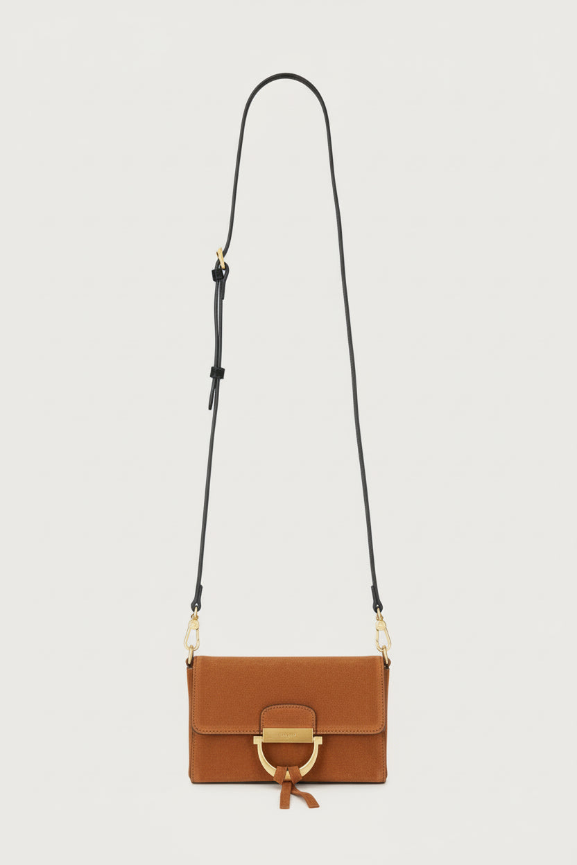 Tan suede handbag with a gold clasp on a light gray background
