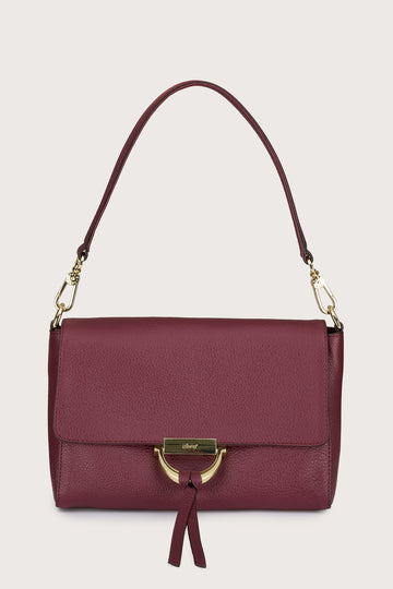 Maroon handbag with gold accents on a beige background