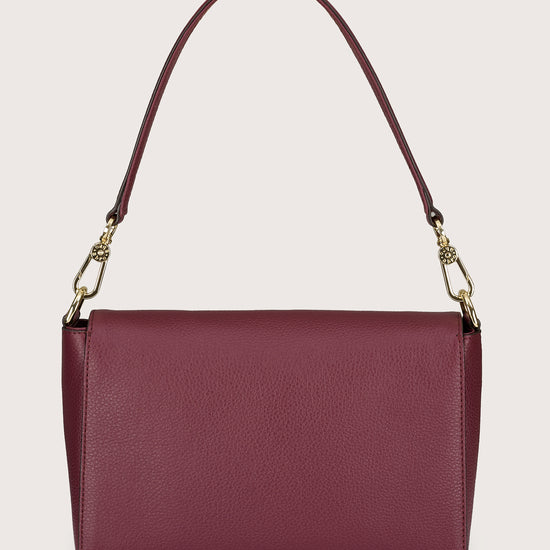 Burgundy handbag with a gold chain strap on a beige background