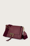 Burgundy handbag with gold accents on a light beige background