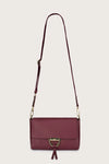 Maroon handbag with a strap on a light gray background