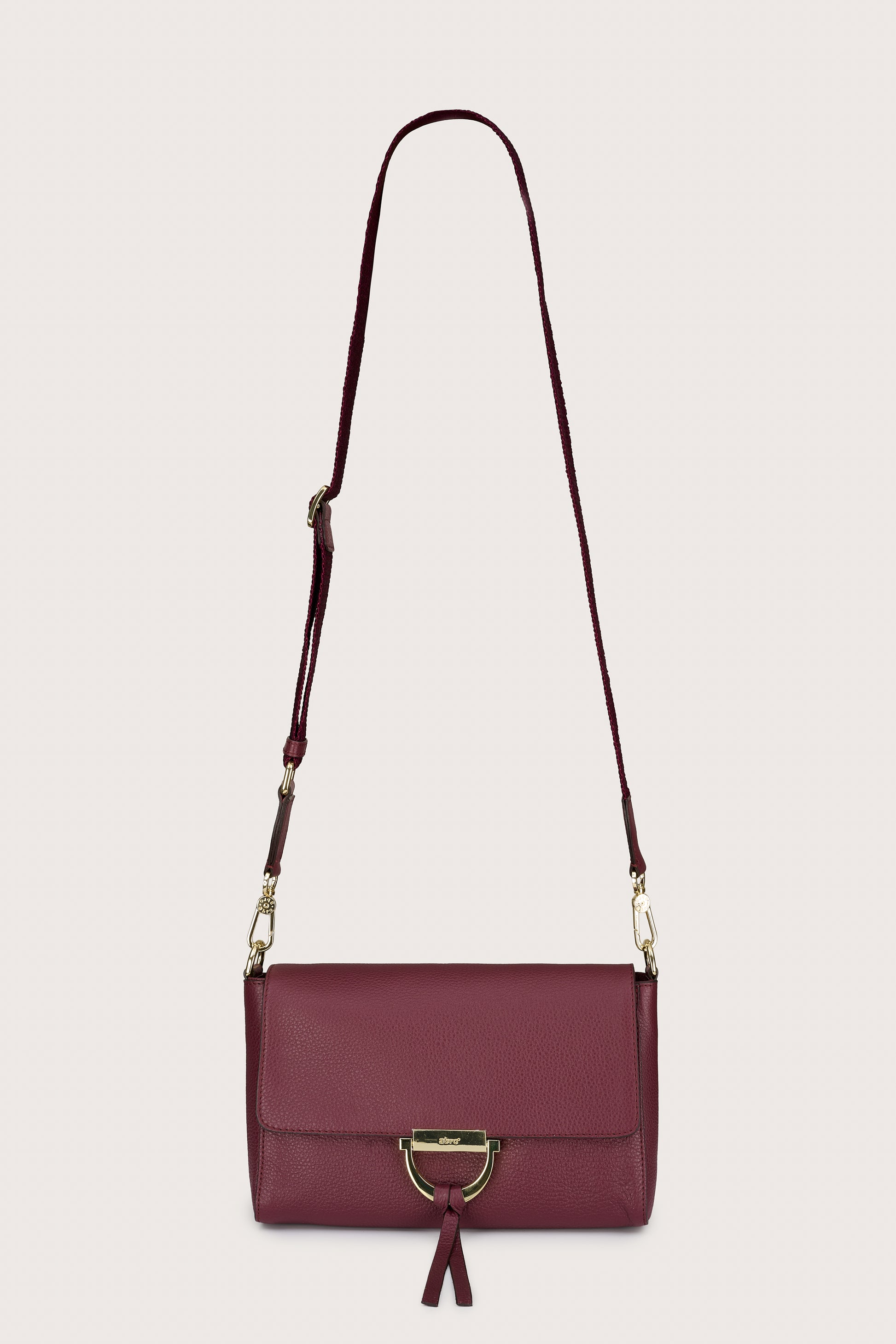 Maroon handbag with a strap on a light gray background