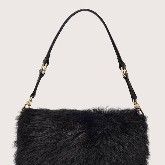 Black fur handbag with gold accents on a light gray background