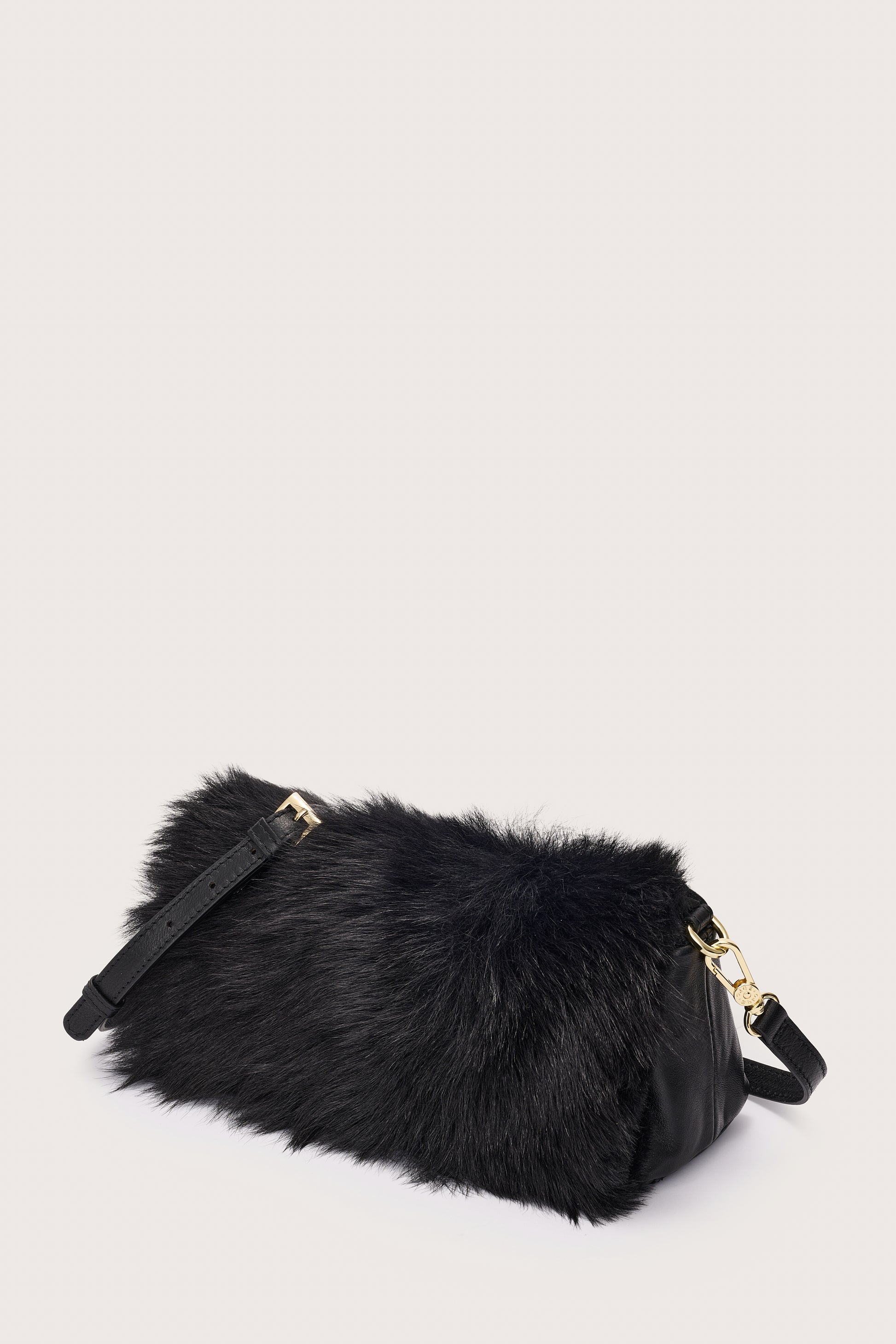 Black fur bag with gold accents on a light gray background