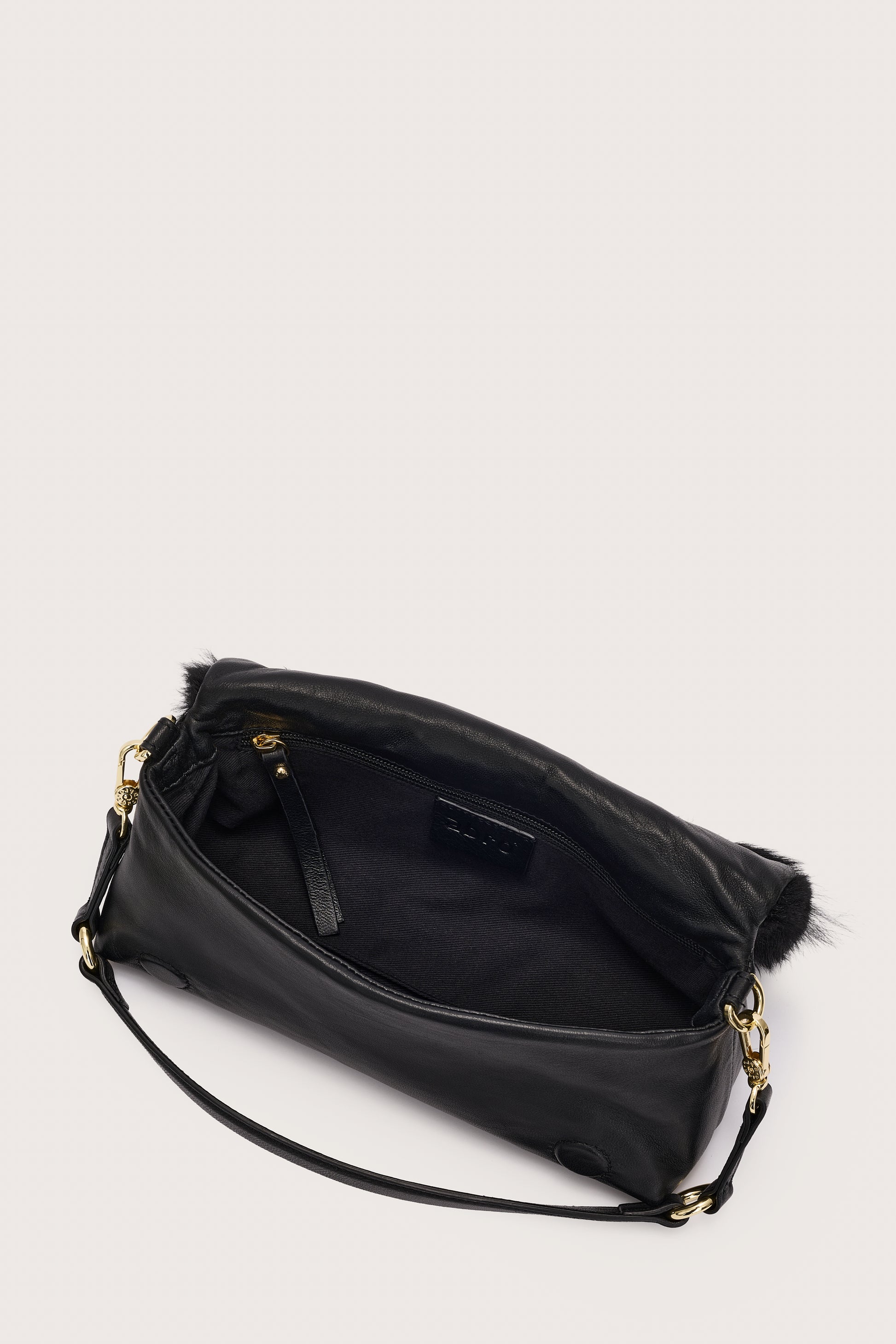 Black handbag with fur trim on a light gray background