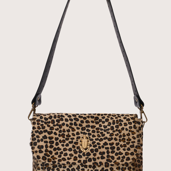 Leopard print handbag with a black strap on a beige background