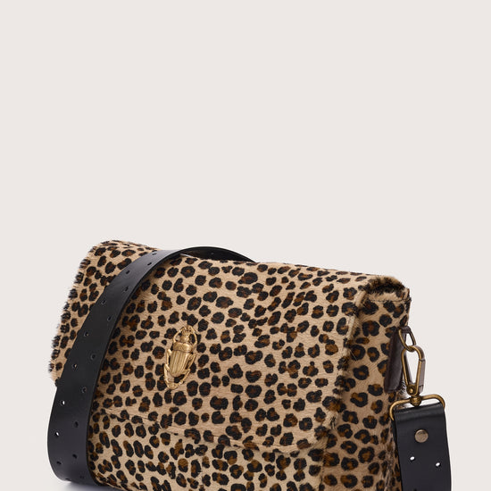 Leopard print handbag with black accents on a light beige background