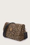 Leopard print handbag with black accents on a light beige background