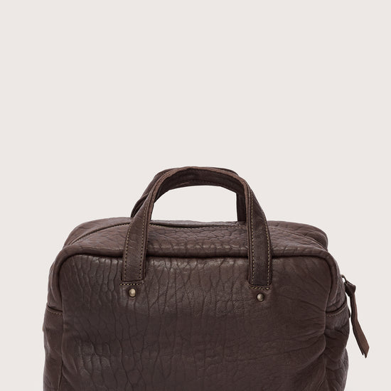 Brown leather bag on a light beige background