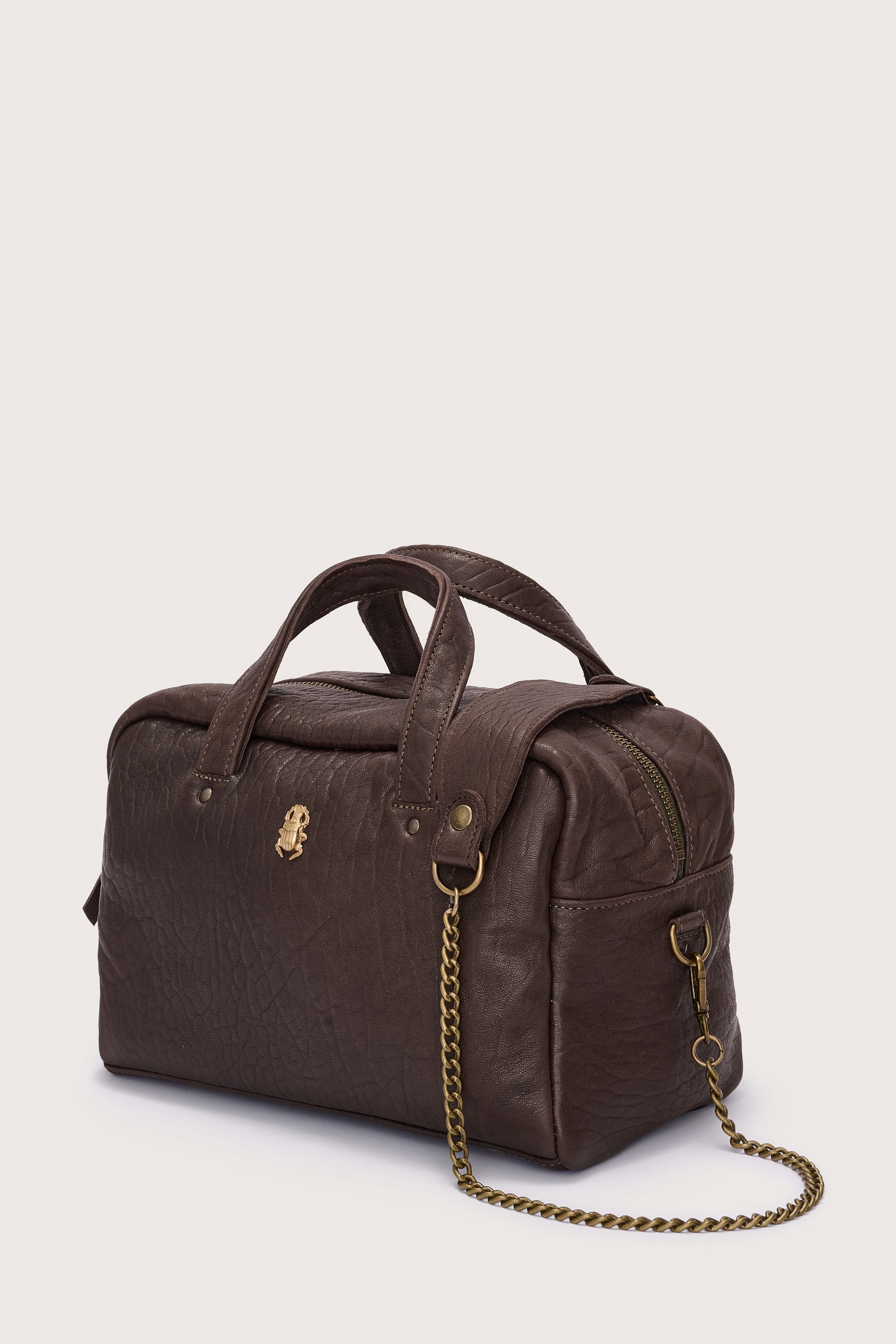 Brown leather bag with a chain detail on a light beige background