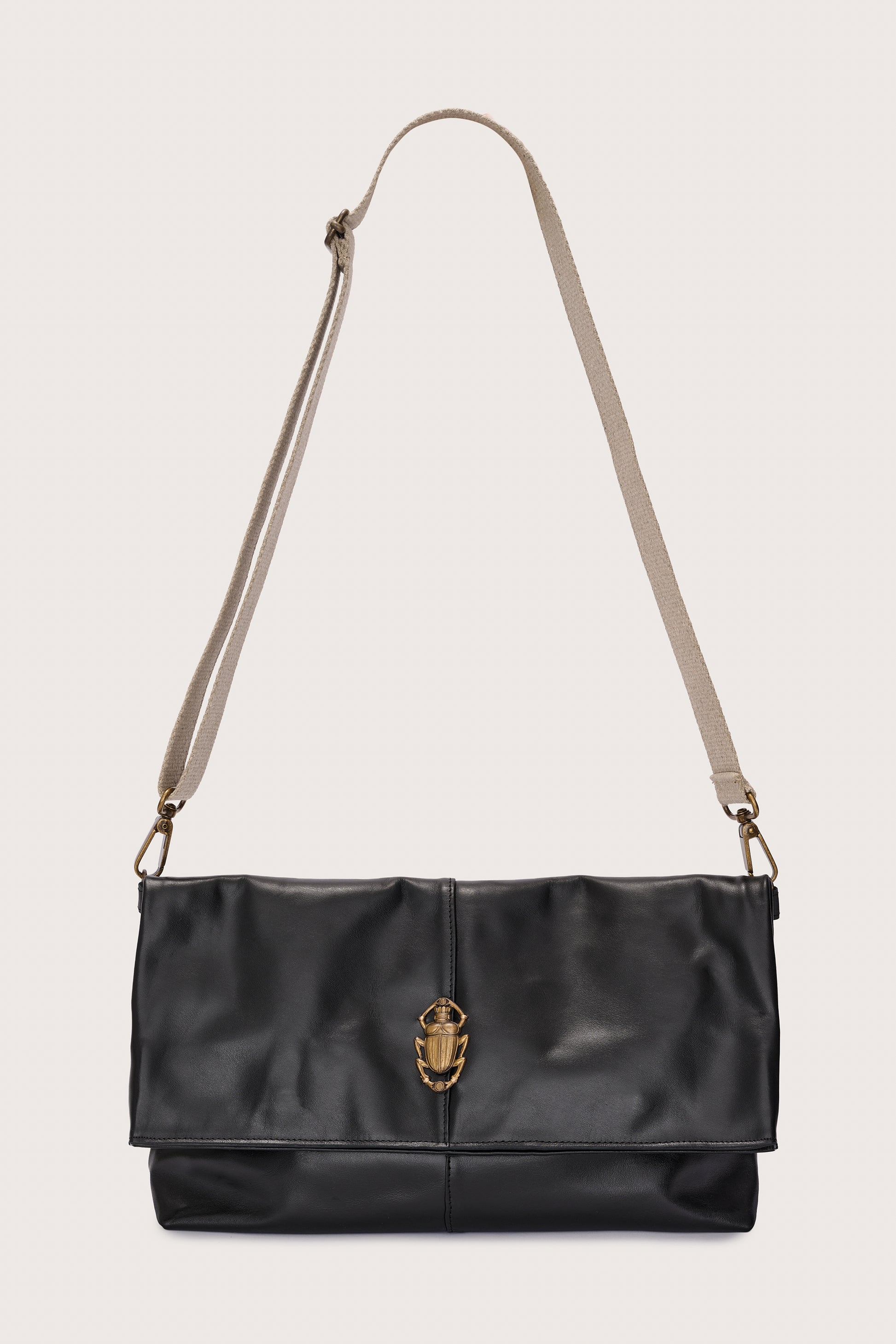 black leather fold over bag with gold scarab stamp and linen strap
