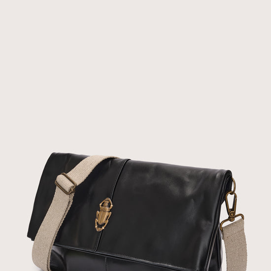 black leather fold over bag with gold scarab stamp and linen strap side view