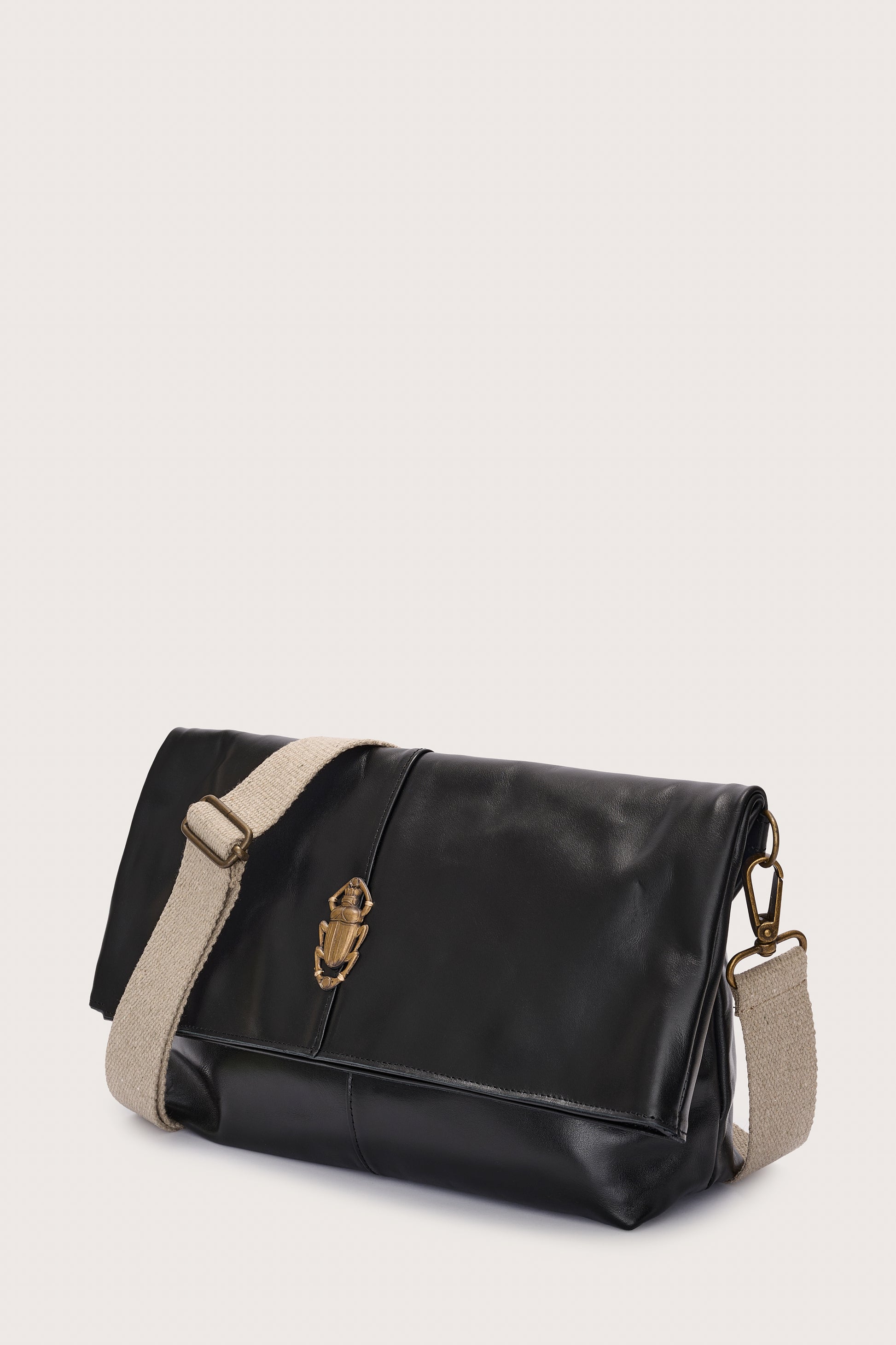 black leather fold over bag with gold scarab stamp and linen strap side view