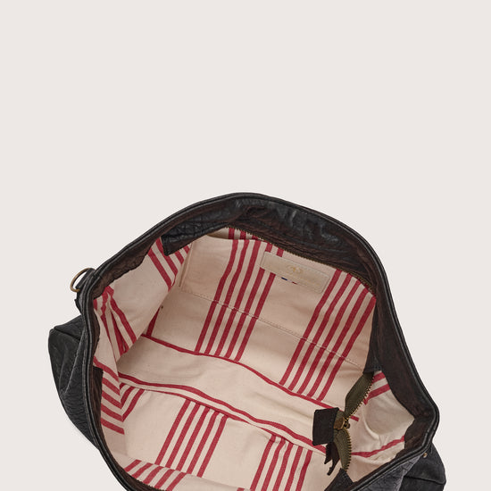 black leather bag with black linen strap and metal stamp detailing inside