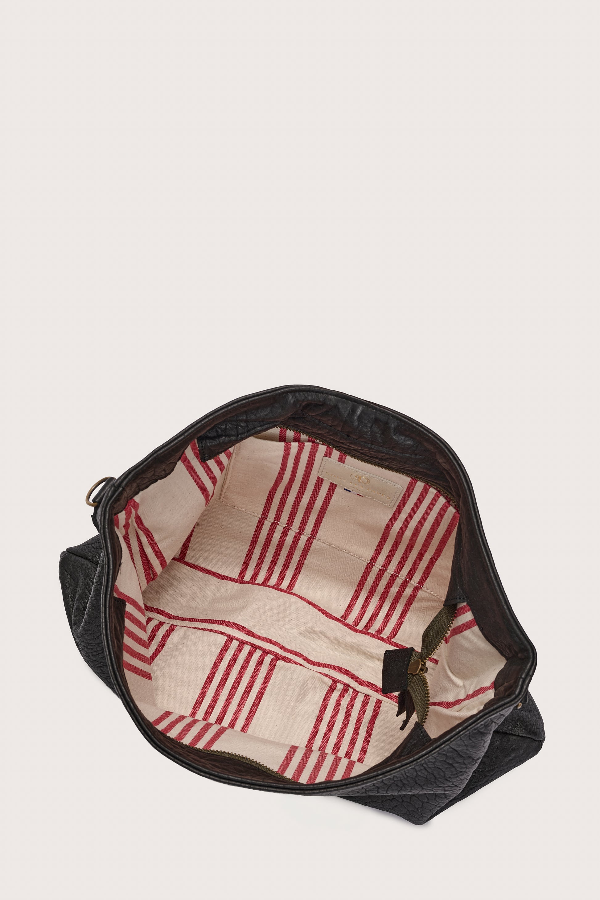 black leather bag with black linen strap and metal stamp detailing inside