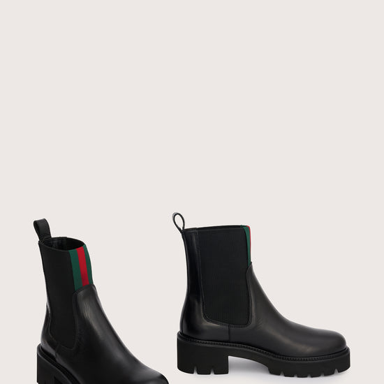 chunky black ankle boots with elasticated panels on side and red/green stripe on the front side view