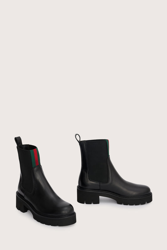 chunky black ankle boots with elasticated panels on side and red/green stripe on the front side view