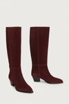 Pair of maroon suede knee-high boots on a light gray background