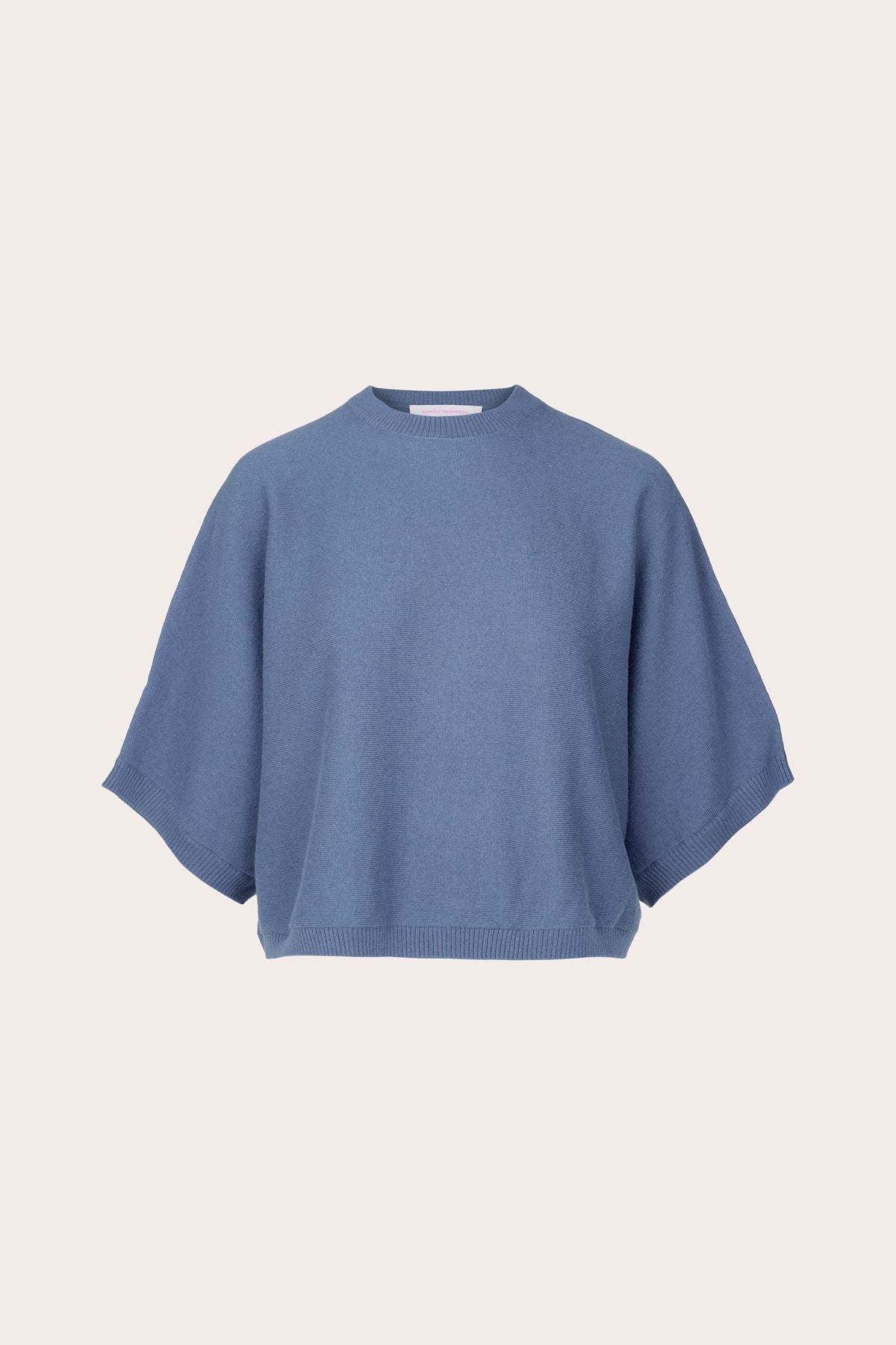 A dusty blue knit sweater with a relaxed, oversized fit and wide short sleeves, presented on a clean, solid off-white background.