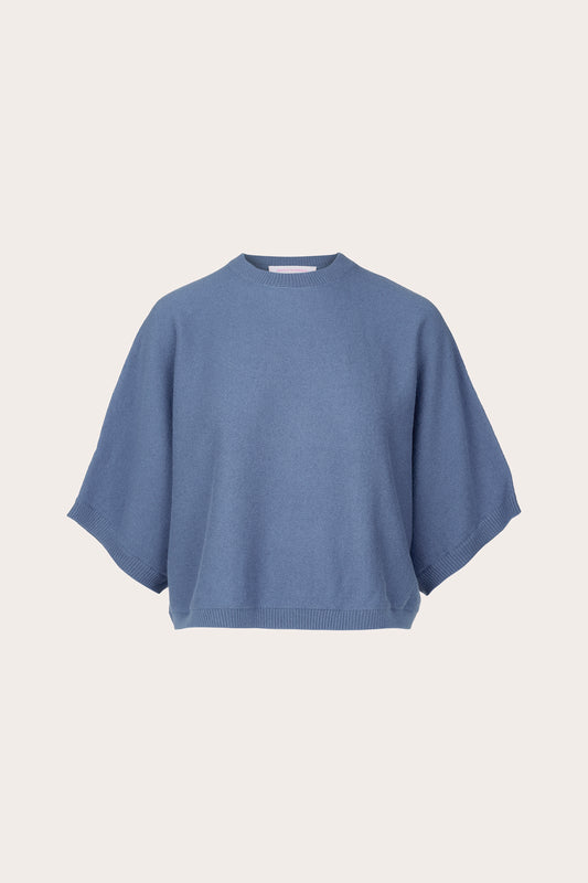 A dusty blue knit sweater with a relaxed, oversized fit and wide short sleeves, presented on a clean, solid off-white background.