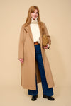 model shot wearing camel edge to edge wool coat, cream knit, blue jeans holding a camel handbag