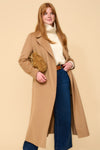 model shot wearing camel edge to edge wool coat, cream knit, blue jeans holding a camel handbag