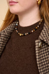 model close up shot wearing brown beaded necklace, brown knit and houndstooth coat.